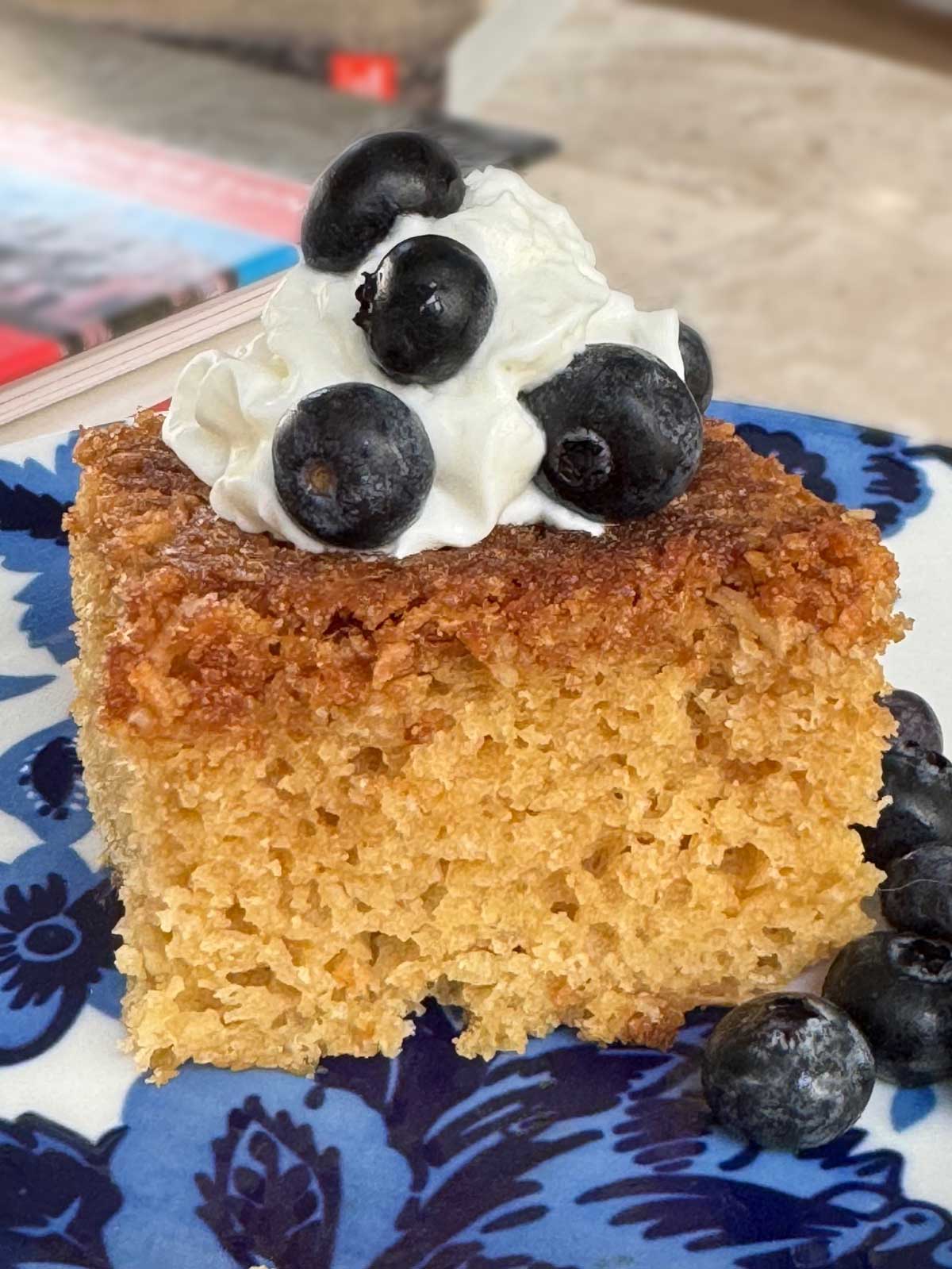 Slice of inverted coconut upside down cake garnished with berries