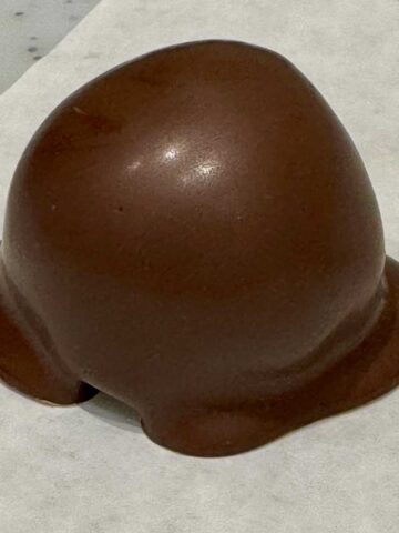 Oreo Truffle draped in chocolate on parchment paper.