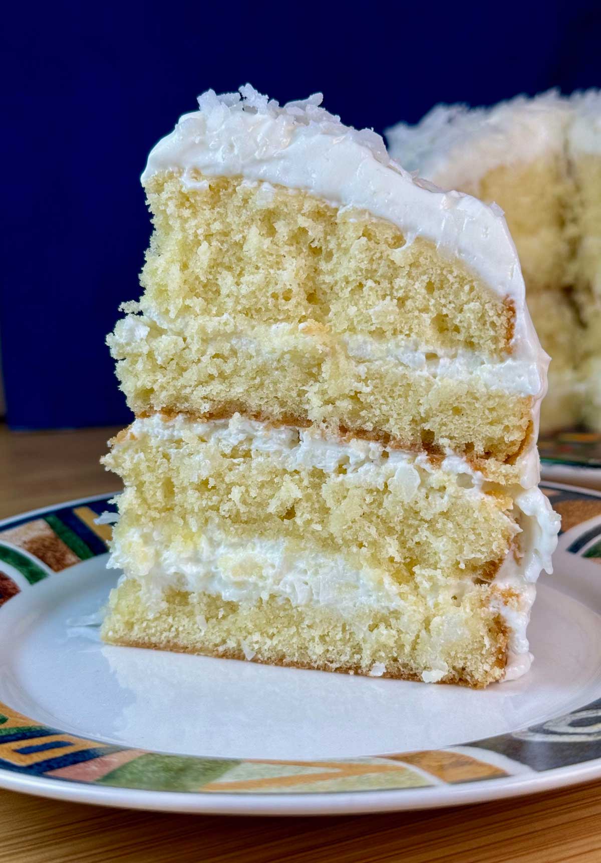 Slice of four layer Celebration Coconut Cake with Sour Cream Icing.