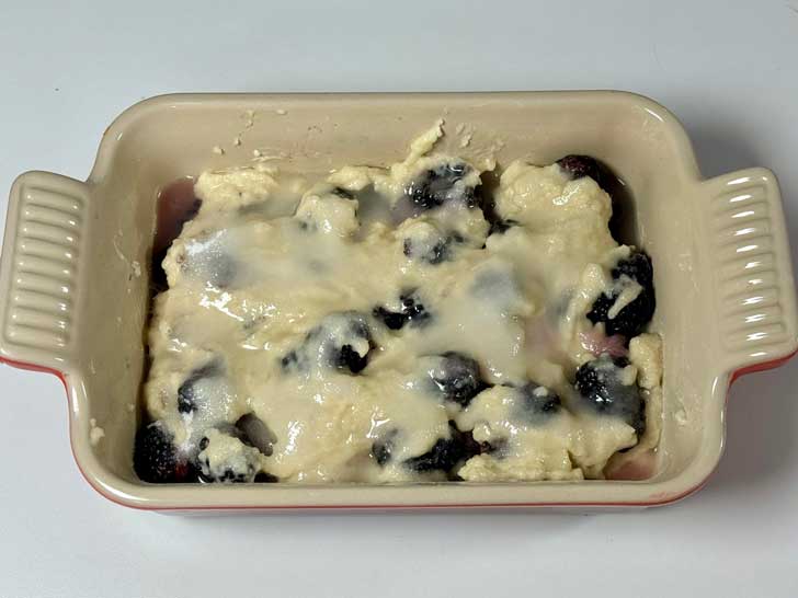 Glossy dough on top of blackberry cobbler.