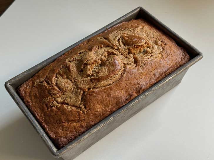 Loaf of quick bread cooling in a loaf pan.