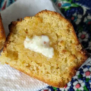 Pineapple Corn Muffin with butter on it and a high crown.