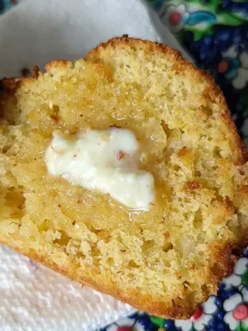 Pineapple Corn Muffin with butter on it and a high crown.