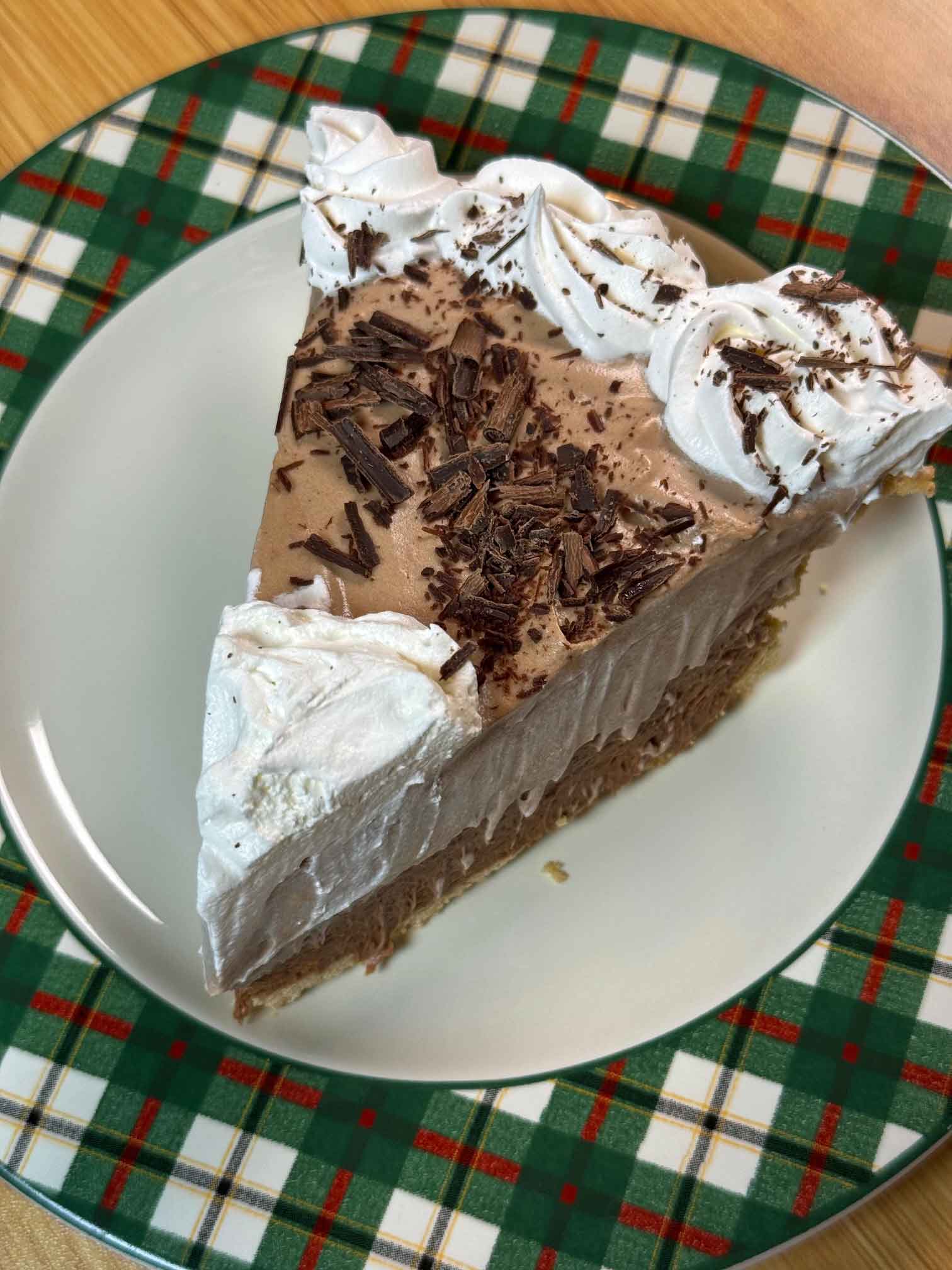 A slice of chocolate pie with two layers of chocolate flavored whipped cream filling.