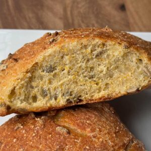 Loaf of Pumpkin Seed Bread with cornmeal sliced to show texture.