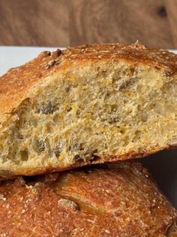 Loaf of Pumpkin Seed Bread with cornmeal sliced to show texture.