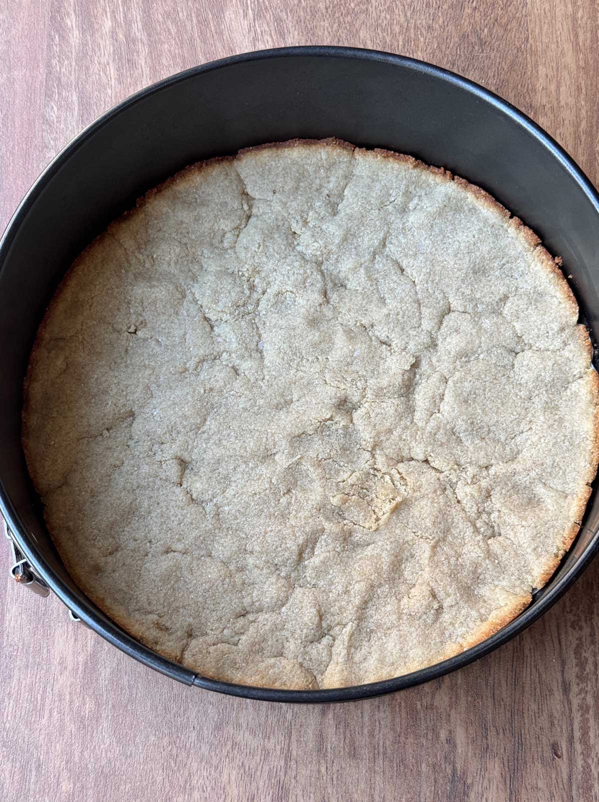 A baked keto cheesecake crust made with almond flour and coconut in an 8 ½ inch springform pan.